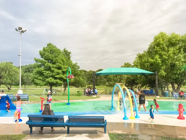 Multikulti-Kinder und Eltern spielen bei sommerlichem Unwetter im Planschpark — Stockfoto