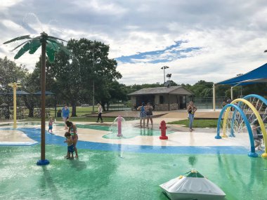 Çok kültürlü çocuklar ve ebeveyn yaz fırtınalı hava altında splash parkta oynuyor