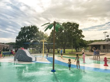 Çok kültürlü çocuklar ve ebeveyn yaz fırtınalı hava altında splash parkta oynuyor