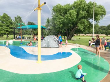 Çok kültürlü çocuklar ve ebeveyn yaz fırtınalı hava altında splash parkta oynuyor