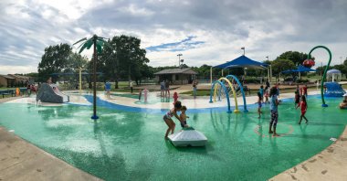 Panoramik çok kültürlü çocuklar ve ebeveyn yaz fırtınalı havaaltında splash parkta oynuyor