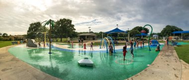 Panoramik çok kültürlü çocuklar ve ebeveyn yaz fırtınalı havaaltında splash parkta oynuyor