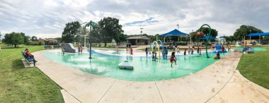 Panoramik çok kültürlü çocuklar ve ebeveyn yaz fırtınalı havaaltında splash parkta oynuyor