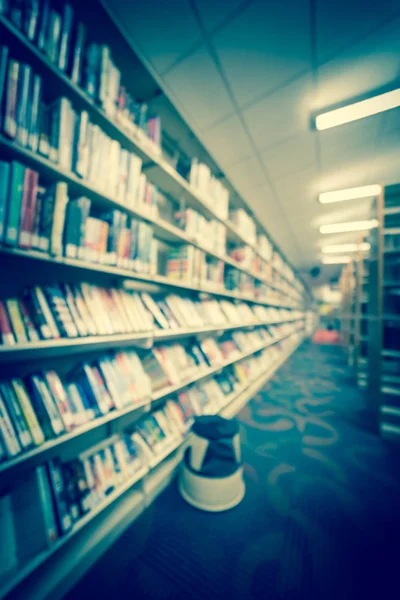 Filtered image blurry background aisle of bookshelf with step stool at public library in USA — Stock Photo, Image