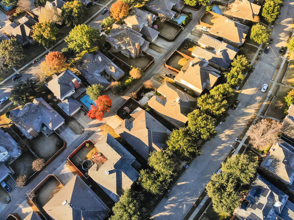 Straight looking aerial view of typical houses with colorful fall color near Dallas, Texas. Fly-over single-family home with large garden, swimming pool. Light snow on the roof in cold early morning