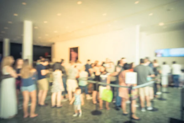 Blurry background diverse people after retractable belt queue at museum entrance