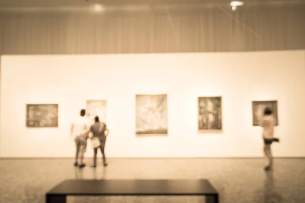 Filtered image blurry background people looking at fine art display at museum in USA — Stock Photo, Image