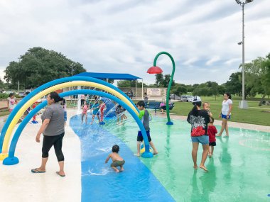 Çok kültürlü çocuklar ve ebeveyn yaz fırtınalı hava altında splash parkta oynuyor