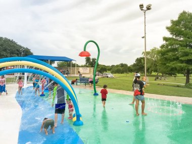 Çok kültürlü çocuklar ve ebeveyn yaz fırtınalı hava altında splash parkta oynuyor