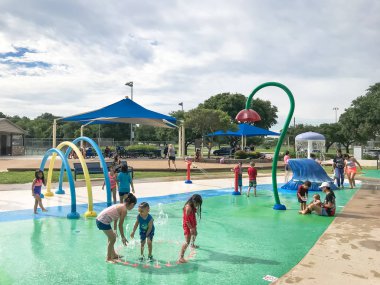 Çok kültürlü çocuklar ve ebeveyn yaz fırtınalı hava altında splash parkta oynuyor