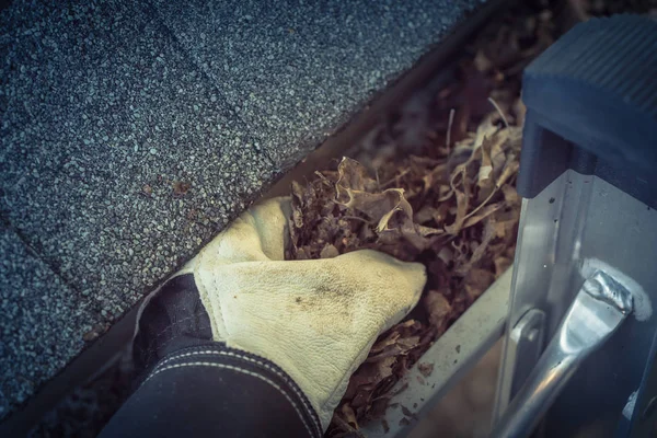 Top View hand in handschoenen op ladder reiniging gedroogde bladeren van goot in Amerika — Stockfoto