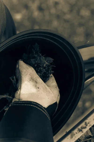 Filtered image close-up hand with gloves drop dried leaves and dirt into bucket from gutter cleaning — Stock Photo, Image