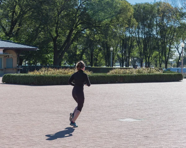 Fitness-Lady mit Sturzsportbekleidung und Kopfhörer läuft im Chicago Park — Stockfoto