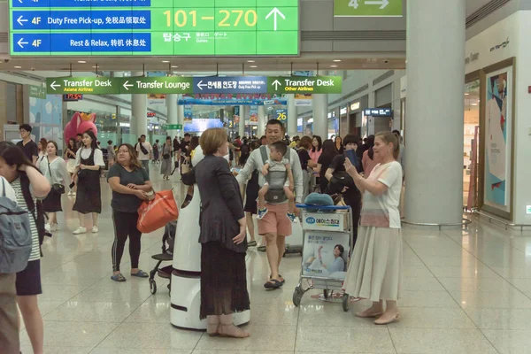 Passageiros tirando fotos com o AIRSTAR Passenger Aiding Robot no aeroporto de Incheon, na Coreia do Sul — Fotografia de Stock