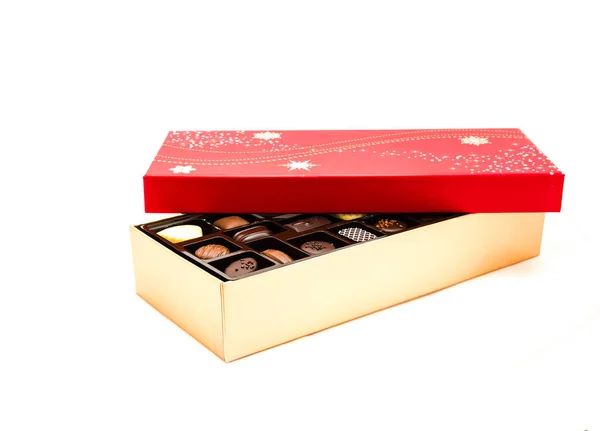 Крупный план частично открытая коробка шоколада с праздничной красной крышкой и ассортиментом трюфелей — стоковое фото