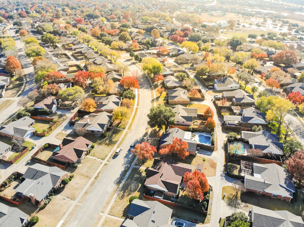 Aerial view residential neighborhood in sunny autumn day with colorful fall foliage. Top of new development subdivision with row of single family house, large backyard and bright orange color leaves