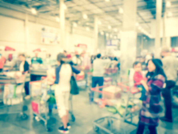 Filtered image blurry background long diverse people queuing at wholesale store checkout counter