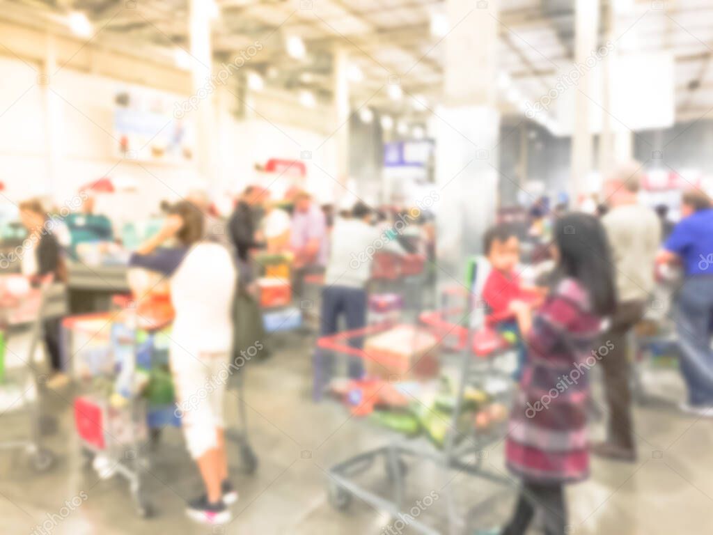 Blurry background long diverse people queuing at wholesale store checkout counter in USA