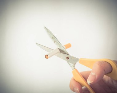 Filtrelenmiş görüntü stüdyosu Asyalı adamın elini çekti sigarayı beyaza izole edilmiş bir makasla kesti
