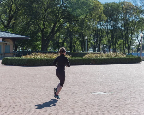 Fitness lady with fall sportswear and headphone running in Chicago park