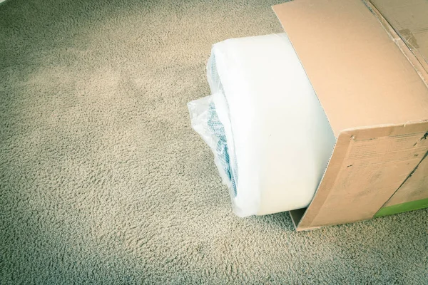 Filtered image close-up roll-packed spring mattresses unbox on carpet floor background — Stock Photo, Image