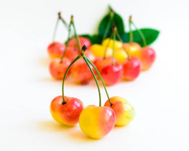 Stüdyo çekimleri iki birleşik kök Rainier kiraz ile bulanık yığın ile beyaz üzerinde yapraklar izole