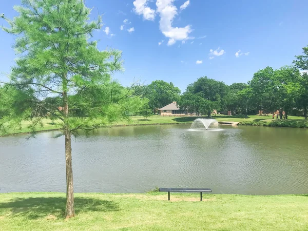 美国德克萨斯州科普费尔市当地公园的长椅上，观赏着清澈的池塘，池塘里有漂浮的装饰喷泉 — 图库照片