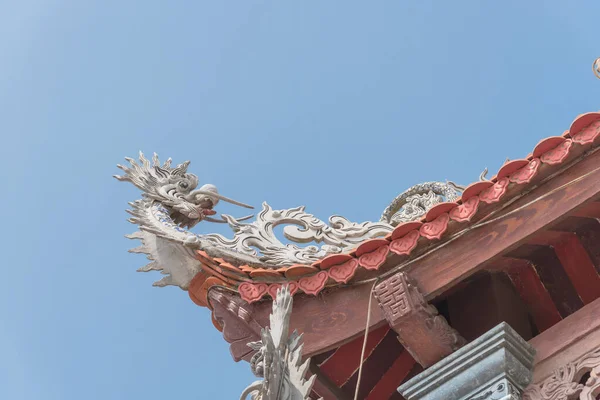 Vista verso l'alto tipico tetto cornice con la scultura testa di drago e tetto di piastrelle rosse in Vietnam — Foto Stock