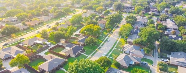 Panoramic Urban sprawl near Dallas, Texas, USA with row of single family houses and large fenced backyard. Aerial view residential neighborhood subdivision surrounded by mature trees