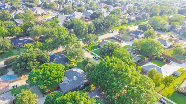 Aerial view an established neighborhood near Dallas, Texas, America in early summer morning. Suburban residential area with detached single family houses and large fenced backyard
