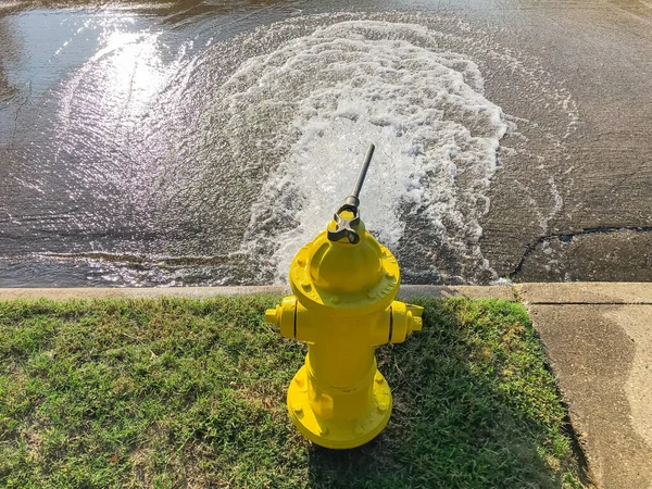 Vista superior hidrante de fogo amarelo jorrando água através de uma rua residencial perto de Dallas, Texas, EUA — Fotografia de Stock