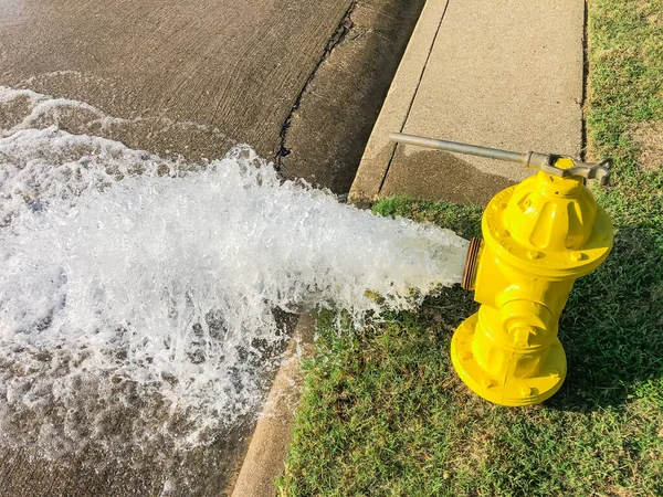 Vista superior hidrante de fogo amarelo jorrando água através de uma rua residencial perto de Dallas, Texas, EUA — Fotografia de Stock