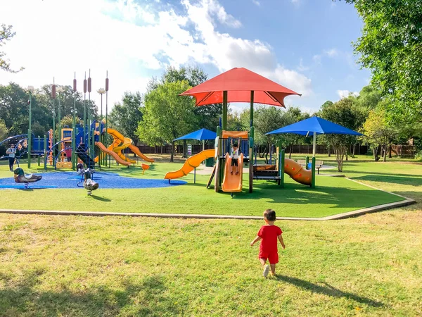Arka manzara Asyalı küçük çocuklar mahalledeki çocuk parkında oynuyorlar ve Flower Mound, TX, ABD 'de güneş gölgesi yelkenleri var. — Stok fotoğraf