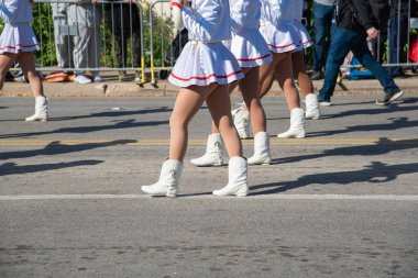 Beyaz etekli göstericiler, kırmızı eşarplar, Dallas 'ta büyük boy J şeklinde baston şeker destekli yürüyüşler. Yaya geçidi sahnesi ve bulanık kalabalık kent şenliğini ve koreografili geleneği çağrıştırıyor. ABD