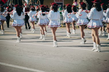 İzleyiciler, aralarında barikatların arkasından gelen çocukların da bulunduğu, beyaz etekli Noel gösterilerini izleyen, kırmızı şapkalıların şeker kamışı aksesuarları taşıyan, neşeli şehir bayramını izleyen ebeveyn omuzlarına odaklanıyorlar. ABD