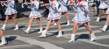 Panorama manzaralı beyaz etekli, kırmızı eşarplı göstericiler Dallas 'ta büyük boy J şeklinde baston şeker aksesuarları giyerler. Yaya geçidi, bulanık kalabalık şehir şenliğini, koreografik geleneği çağrıştırıyor. ABD