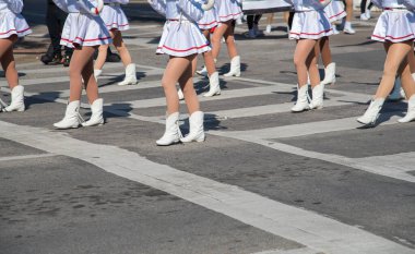 Kırmızı aksanlı beyaz üniformalı baton çevirenler, Noel 'de Dallas geçit töreninde formasyon oluşturuyorlar. Senkronize hareket, çizgili coplar Noel ruhunu ve gençlik performansını ön plana çıkarıyor. ABD