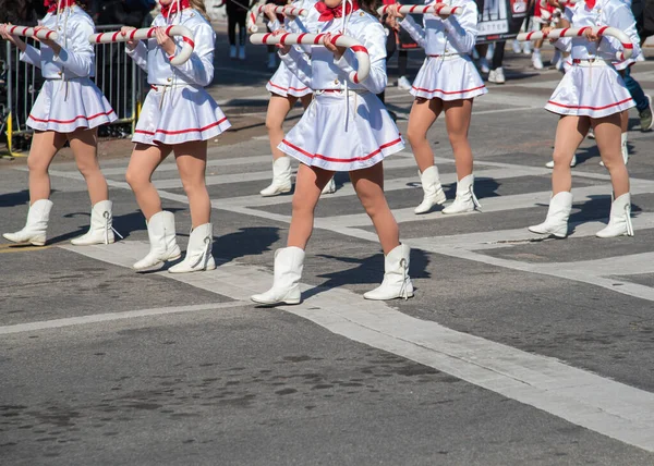 Kırmızı aksanlı beyaz üniformalı baton çevirenler, Noel 'de Dallas geçit töreninde formasyon oluşturuyorlar. Senkronize hareket, çizgili coplar Noel ruhunu ve gençlik performansını ön plana çıkarıyor. ABD