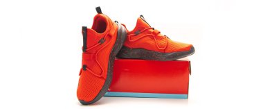 Panorama manzaralı kırmızı spor ayakkabılar siyah benekli lastik tabanlar ve beyaz arka planda izole edilmiş ağ yükselticileri ile uyumlu ayakkabı kutusunda sergilenir. Düz ve yassı tasarım vitrinler ambalaj, zinde, perakende. ABD