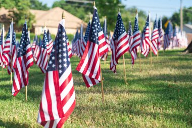 One flag stands in crisp focus against a softly blurred residential houses and neighborhood street, capturing the emotional clarity of remembrance in Texas patriotic 9/11 memorial landscape. USA
