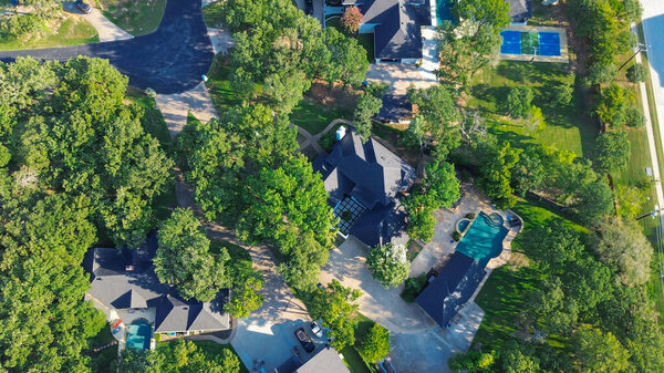 Tennis courts in luxury mansion homes in Lantana, Texas, surrounded by dense greenery, spacious backyard with swimming pools. Upscale suburban residential neighborhood suburbs Dallas Forth Worth. USA