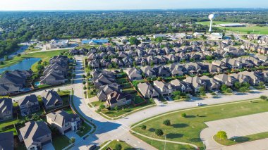 Water tower in new construction homes master planned community in Lantana, Texas, landscaped pond with walking paths, bordered by undeveloped greenbelt, forested land to horizon, school district. USA
