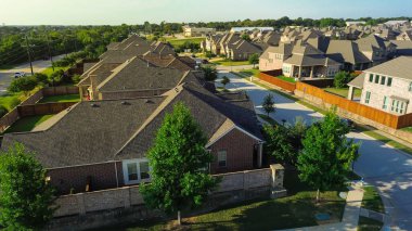 Brick wall fence enclosure marks formal entrance from FM 407 local highway into managed residential district, manicured landscaping, signage, access control for the community in Lantana, Texas. USA
