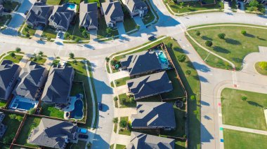 Green spaces from school, park near upscale two-story homes with sloped roofs, pools, patios, fenced yards and well-manicured yards in Lantana, Texas. Balanced suburban land use in suburbs Dallas. USA