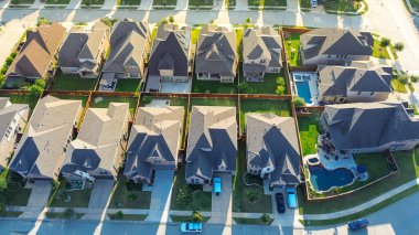 Pools and patios in fenced backyard of new development suburban neighborhood in Lantana, Texas, closely spaced homes with gabled roofs, manicured lawns in uniform architecture and landscaping. USA