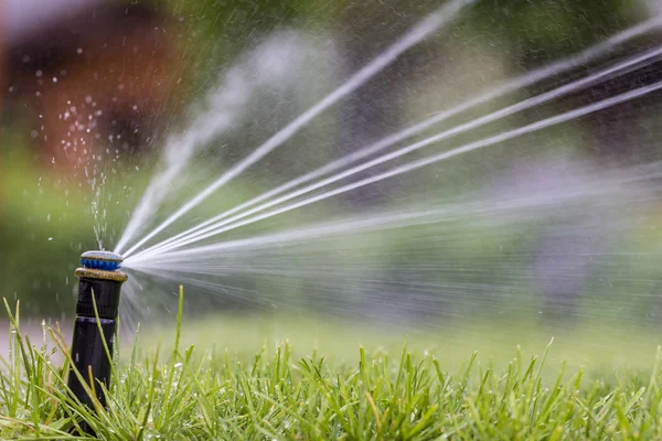 Automatic sprinkler system watering the lawn on a background of green grass — Stock Photo, Image