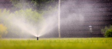 Otomatik fıskiye sistemi yeşil çimlerin arka planında çimenleri suluyor, yakın plan