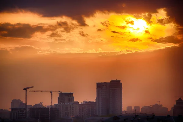 Der Sonnenuntergang über der Stadt ist ein leuchtend orangefarbener Himmel und glänzende Wolken — Stockfoto