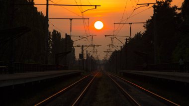 Gün batımında, bir platform ozhidayuschimi yolcular ile Demiryolu demiryolu