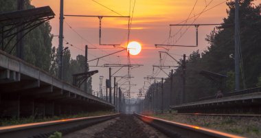 Gün batımında, bir platform ozhidayuschimi yolcular ile Demiryolu demiryolu